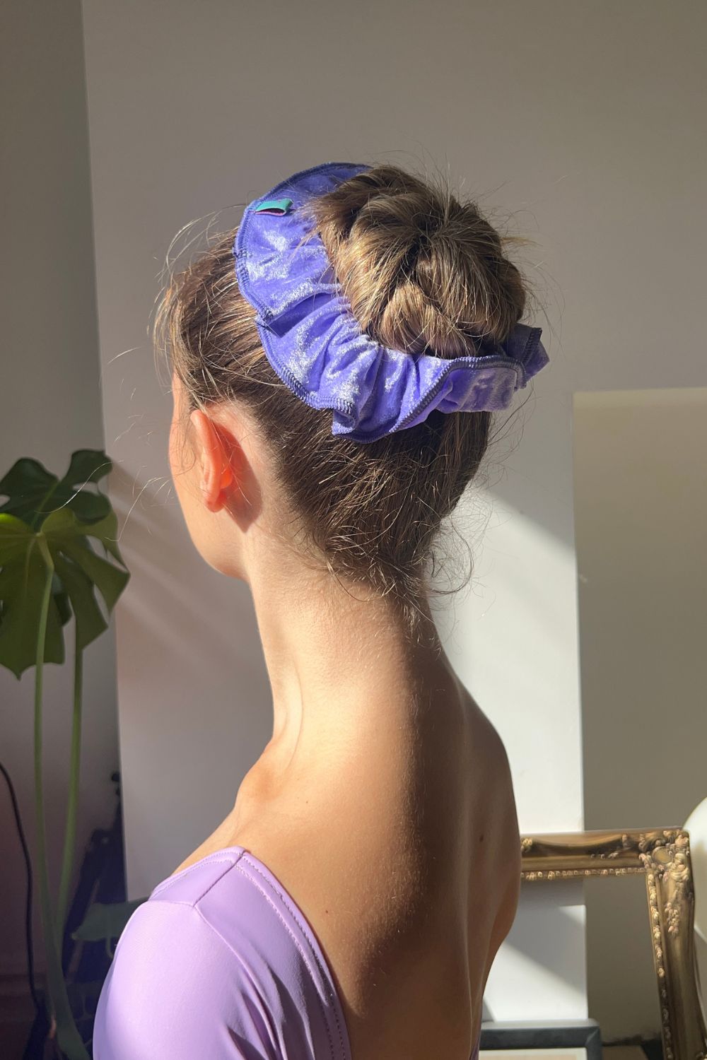 ballerina wearing light purple crushed velvet hair scrunchie around ballet bun.