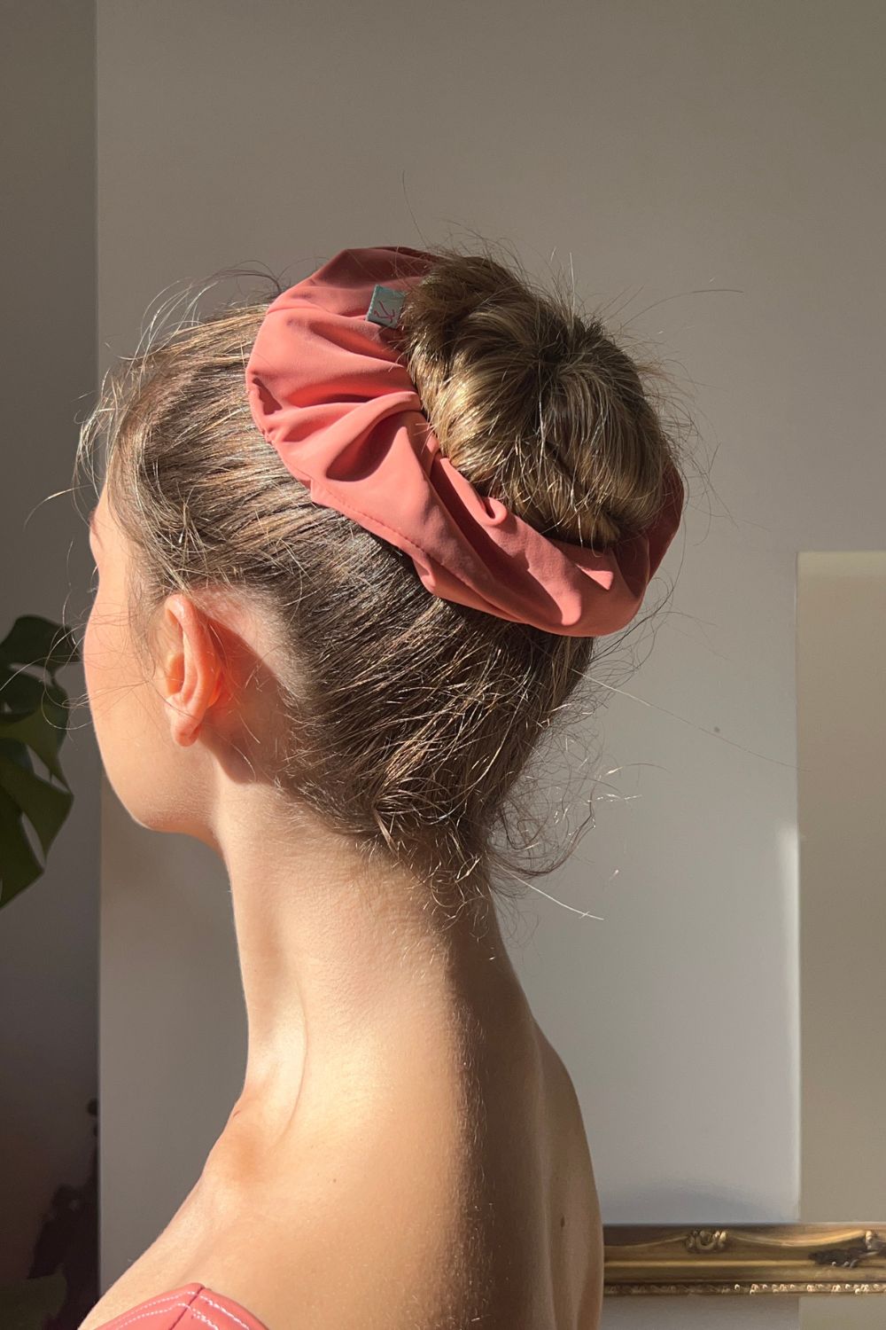 ballerina wearing peach coloured hair scrunchie around ballet bun.