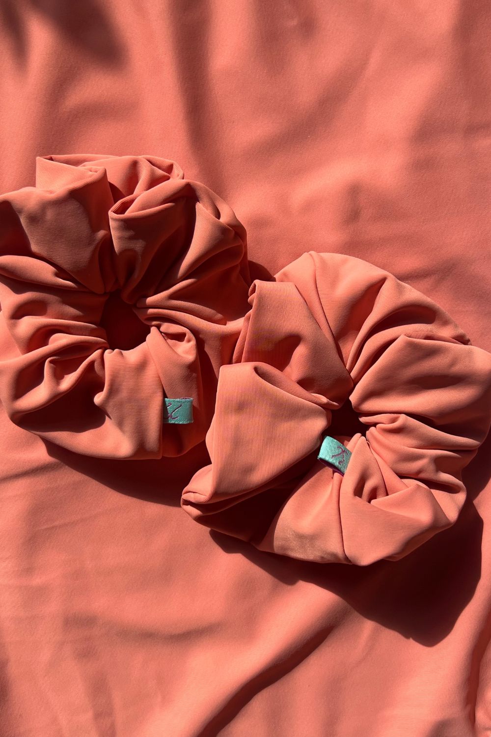 two peach coloured hair scrunchies on top of peach background.