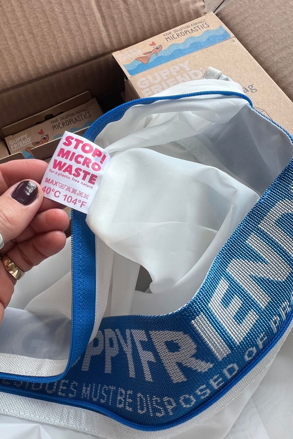 Open GUPPYFRIEND washing bag with blue trim and a care label reading “STOP! MICRO WASTE” and maximum 40°C.