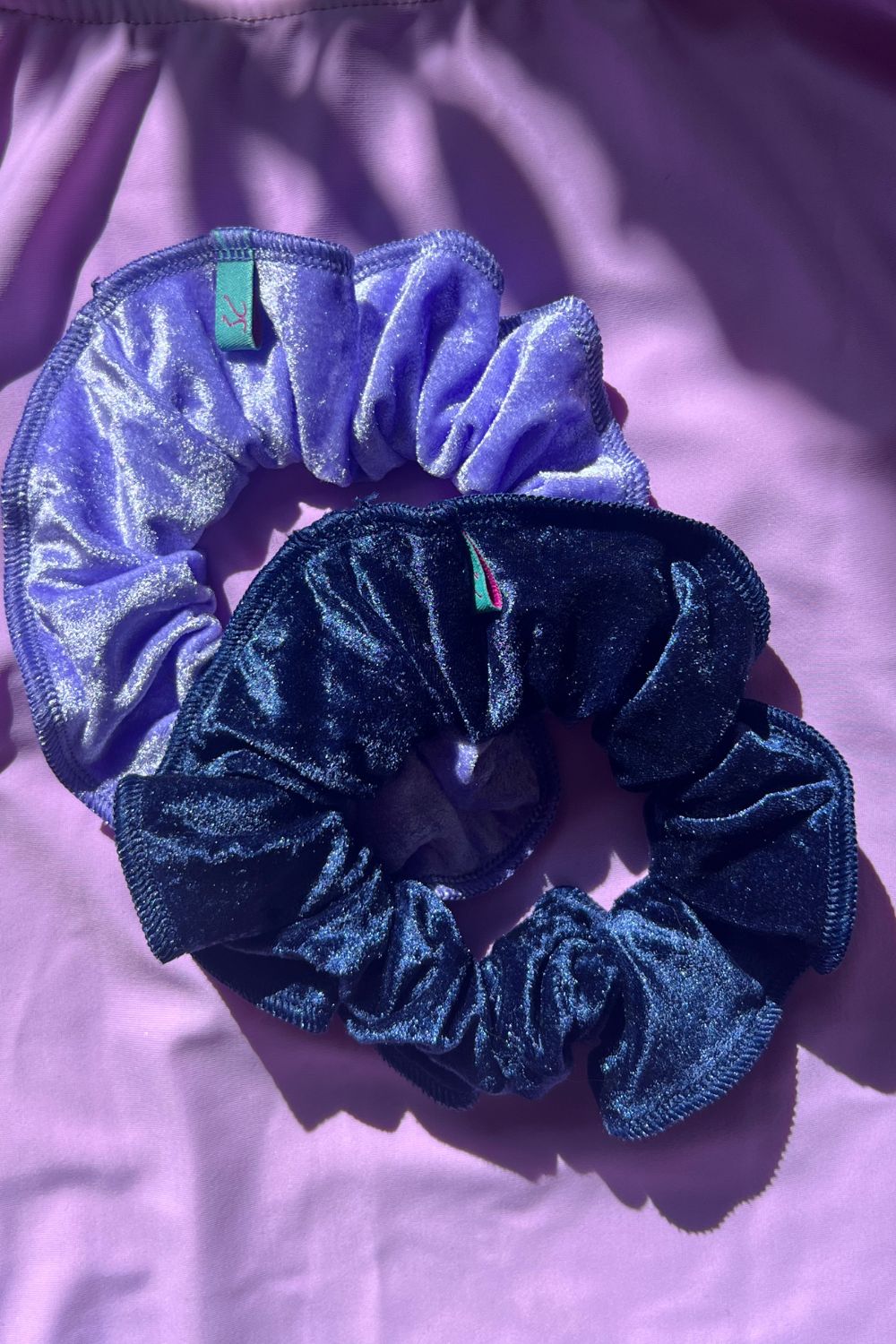 two crushed velvet hair scrunchies, one light purple, one navy blue. 