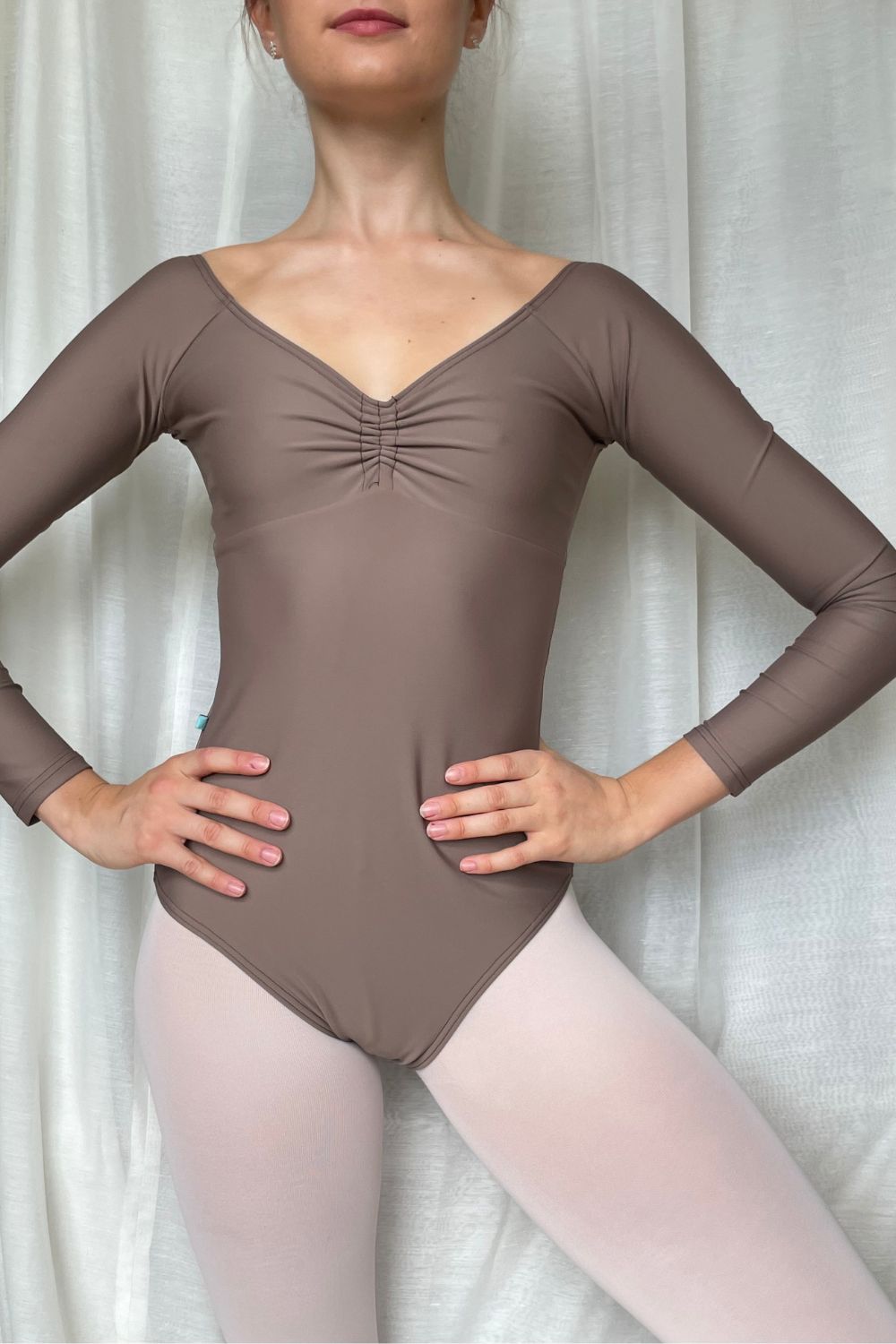 Front close-up of the Mocha Alexandria leotard, showing its ruched sweetheart neckline and long sleeves, worn with pink ballet tights.