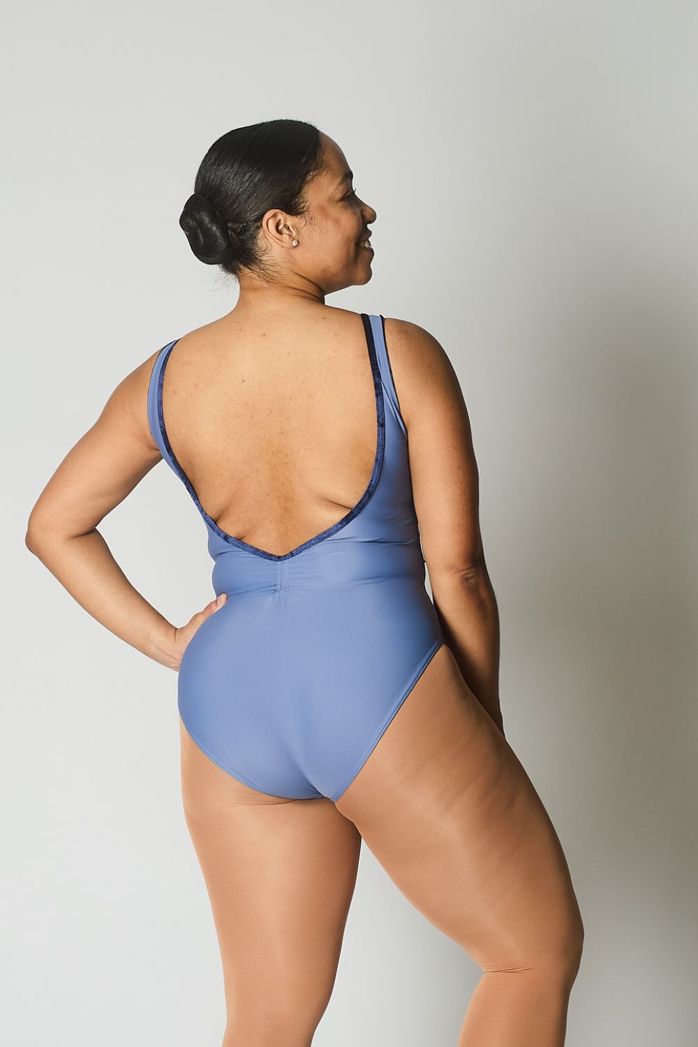 Woman wearing a blue leotard against a plain background