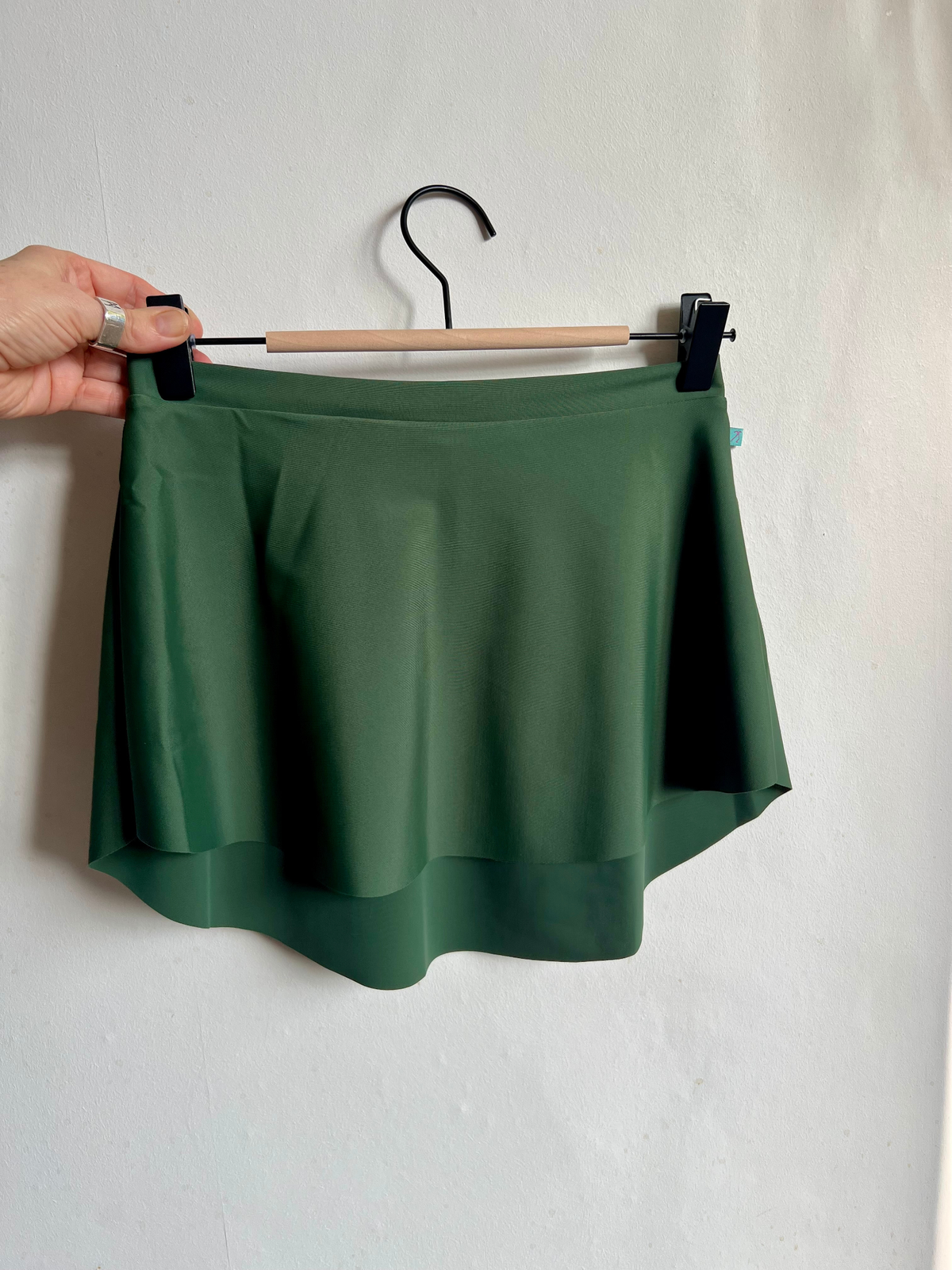 green ballet skirt SAB style on a hanger against a white wall 