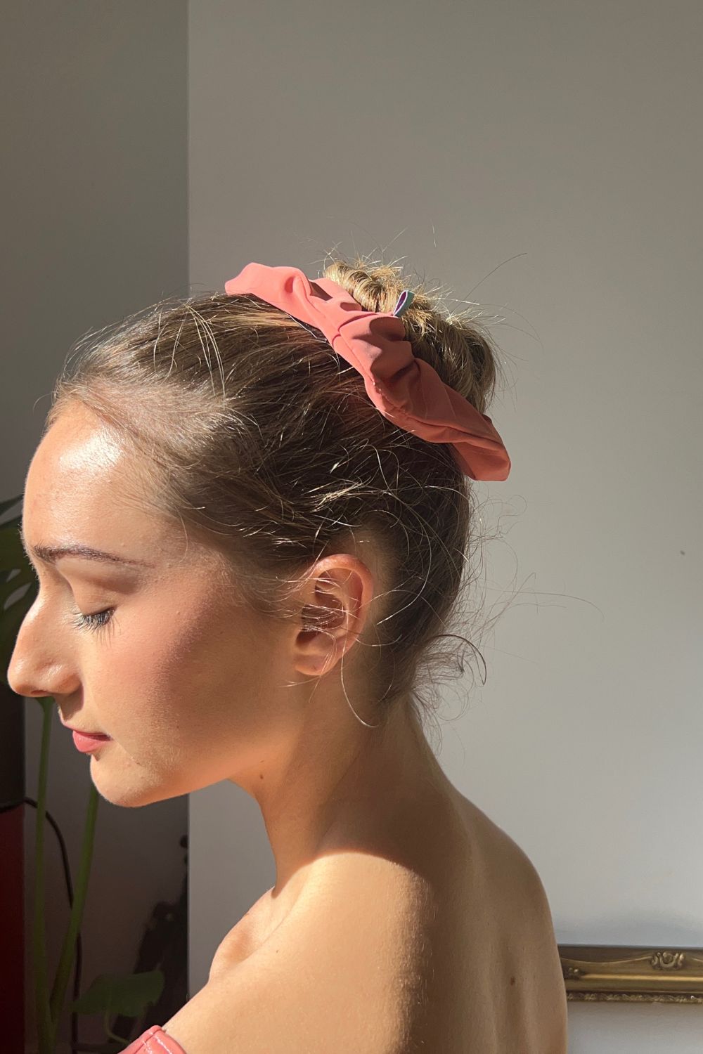 Ballet dancer wearing a peachscrunchie in her hair against a plain background