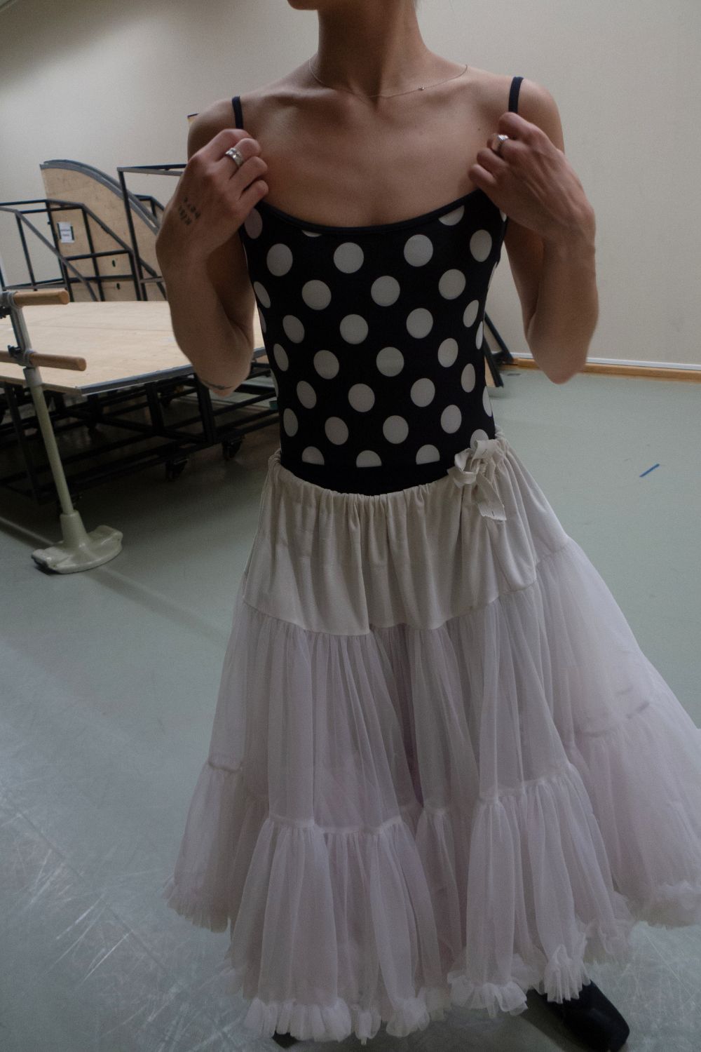 A professional ballerina wearing the Cali Camisole black polka dot ballet leotard styled with a white tutu skirt