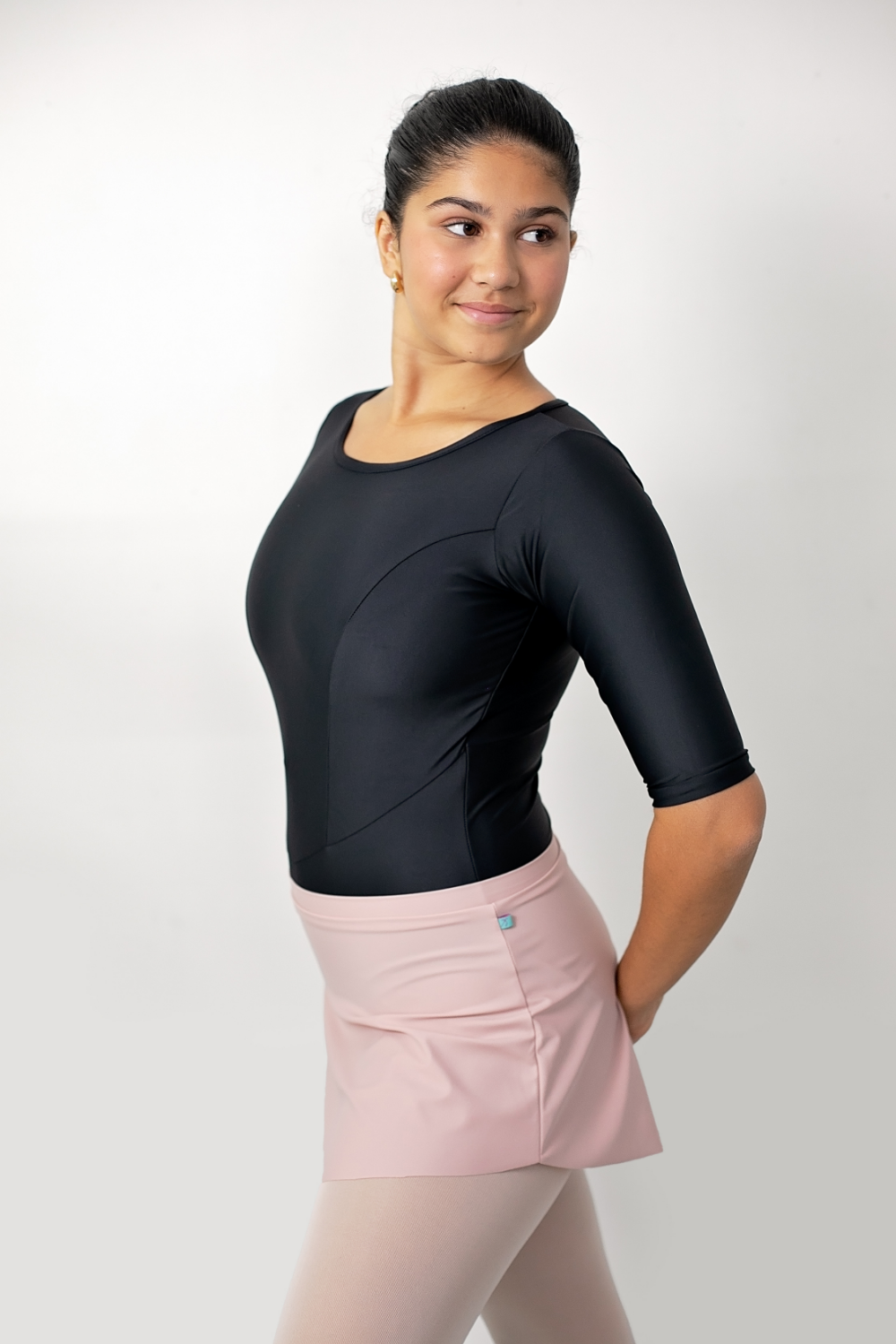dancer wearing a black ballet leotard with full coverage and pink ballet tights and skirt 